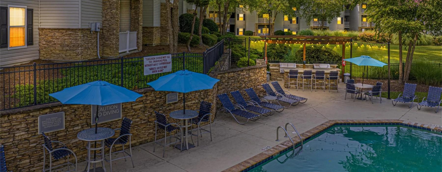 a pool with chairs and umbrellas next to a building