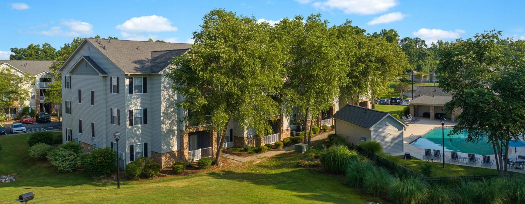 a large green lawn with trees and buildings in the background