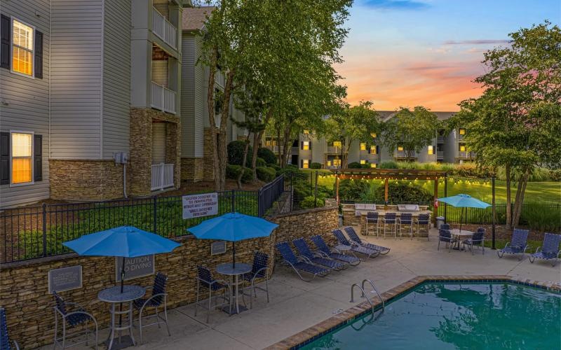 a pool with chairs and umbrellas next to a building
