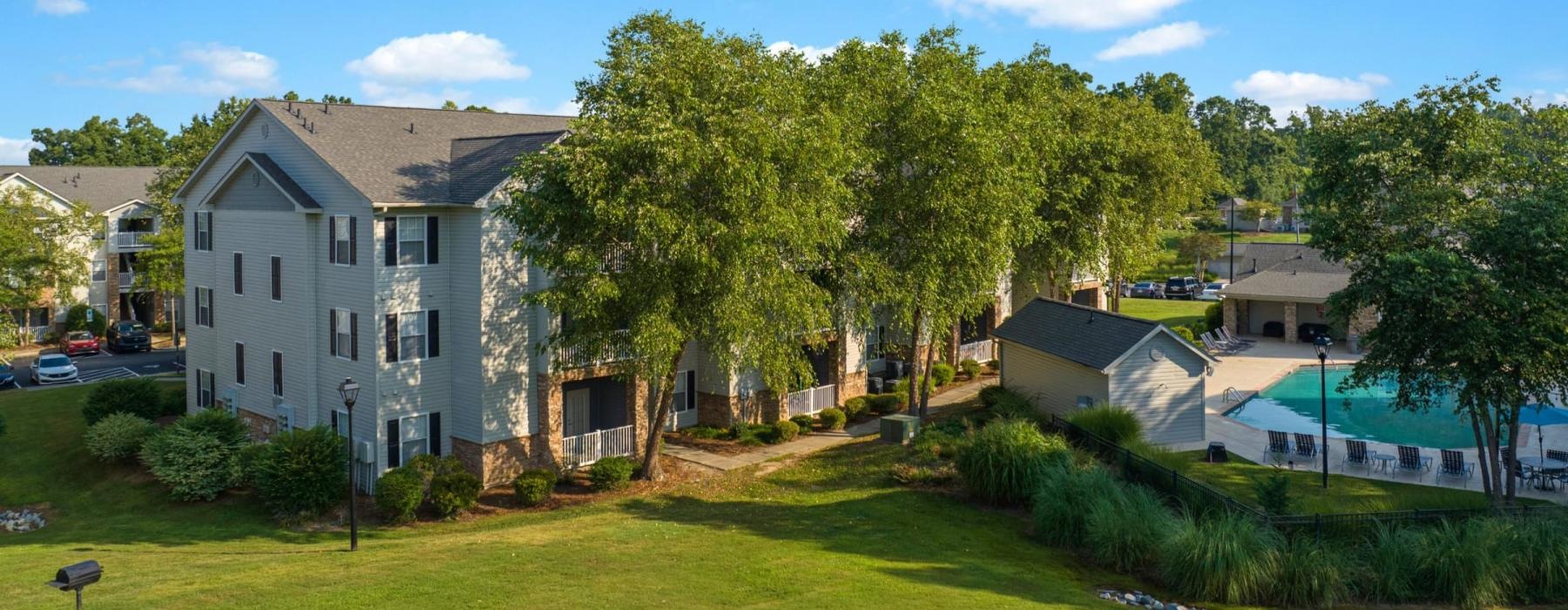 a large green lawn with trees and buildings in the background